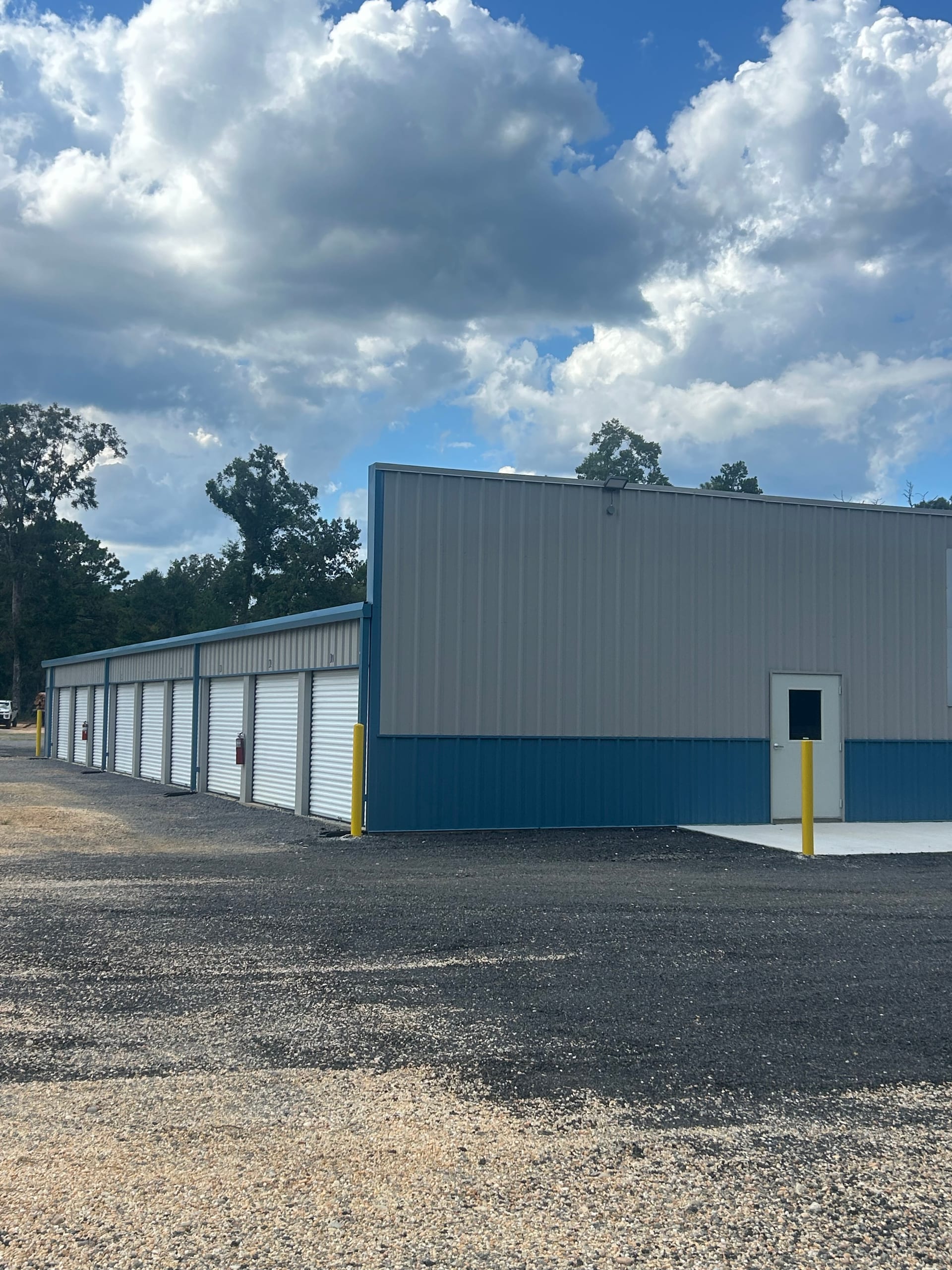 Row of white roll-up door storage units beside the office building